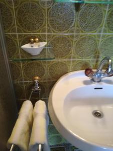 ein Bad mit einem Waschbecken und Handtüchern an einer gefliesten Wand in der Unterkunft Gasthof Platzschmied in Guttaring