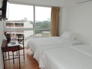 Habitación de hotel con 2 camas, escritorio y ventana en Departamentos Golf Park - Surco, en Lima