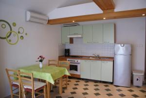 a kitchen with a table and chairs and a refrigerator at Apartments Robert in Porat