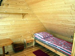 a bed in a wooden room with a wooden wall at Letniskowy domek z bala w Mikołajkach in Mikołajki