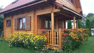a wooden cabin with flowers in front of it at Letniskowy domek z bala w Mikołajkach in Mikołajki