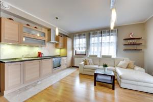 een woonkamer met een witte bank en een keuken bij Seaside with Sunny Terrace in Gdańsk