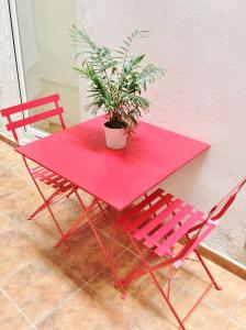 マドリードにあるApartamento Deliciasのピンクのテーブル(鉢植えの植物と椅子2脚付)