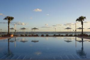a large swimming pool with palm trees and umbrellas at Real Marina Hotel & Spa in Olhão