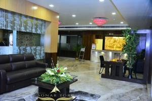 a lobby with a black leather couch and a table at Hotel Sonar Tori in Agartala
