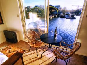 a table with chairs and a bottle of wine on a balcony at Houseboat Concordia B&B in Amsterdam