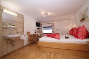 a bedroom with a bed with red pillows and a sink at Pfandlhof in Walchsee