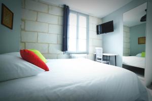 un letto bianco con cuscini rossi e gialli in una stanza di Hotel de la gare a Château-du-Loir