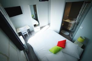 una camera con letto bianco e cuscino rosso e verde di Hotel de la gare a Château-du-Loir Altre 2 foto