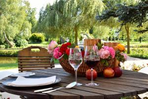 einen Holztisch mit zwei Gläsern Wein und Blumen in der Unterkunft PARKHOTEL - Rosarium in Uetersen