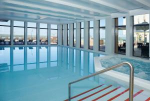 a swimming pool in a building with windows at Real Marina Hotel & Spa in Olhão