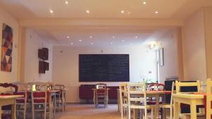 a restaurant with tables and chairs and a chalkboard on the wall at Hotel de la gare in Château-du-Loir