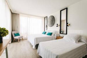two beds in a hotel room with white walls at Hotel Almirante in Alicante