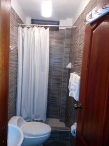 a bathroom with a white shower curtain and a toilet at Paradisse in Huacho