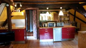 a kitchen with red cabinets and a counter with a microwave at Gîte "Le cosy" in Turckheim