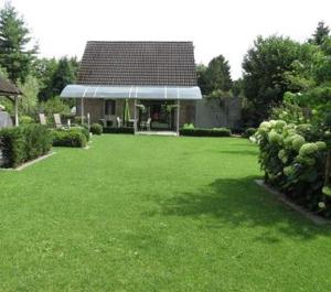 a yard with a house with a green lawn at Stropershuisje in Stekene