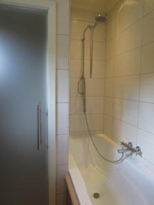 a bathroom with a bath tub with a shower at Stropershuisje in Stekene