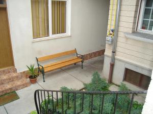 un banc en bois assis sur un trottoir à côté d'un bâtiment dans l'établissement Guesthouse Daniel, à Oradea