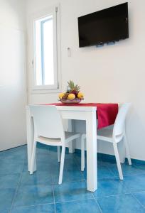 サン・ヴィート・ロ・カーポにあるAppartamento Giuliaの白いダイニングテーブル(椅子2脚付)、テレビが備わります。