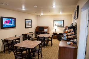 a waiting room with tables and chairs and a tv at My Place Hotel-Kansas City/Independence Mo in Independence