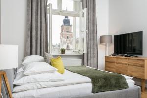 a bedroom with a bed and a window with a clock tower at Venetian House Market Square Aparthotel in Krakow