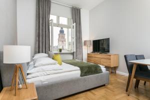 een slaapkamer met een bed en een televisie en een tafel bij Venetian House Market Square Aparthotel in Krakau