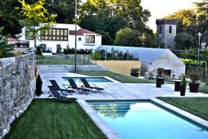 a swimming pool with chairs and a house at Casa do Passal Country House in Paço de Sousa