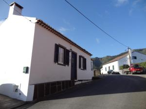 a white house with a black door on a street at Casa do Rei in Furnas