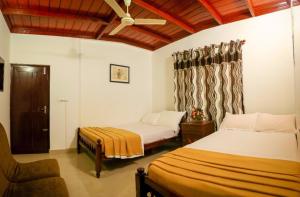 a bedroom with two beds and a chair at Elroy Homestay in Kalpetta