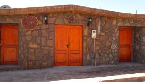 a stone building with orange doors and a sign on it at Hostal Casa Flores in San Pedro de Atacama