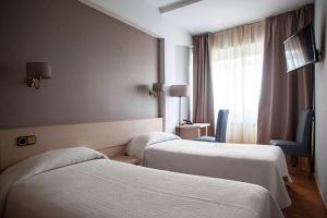 a hotel room with two beds and a window at Hotel Brial in Perillo