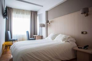 Un dormitorio con una gran cama blanca y una ventana en Hotel Brial, en Perillo