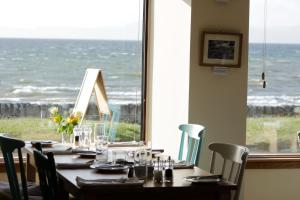 a dining room table with chairs and a glass of wine at Caledonian House in Portmahomack