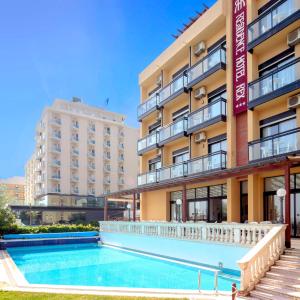 a hotel with a swimming pool in front of a building at Rex Residence Hotel in Cattolica