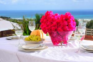 Kivotos Villa في Maroulás: طاولة مع إناء من الزهور الزهرية والعنب