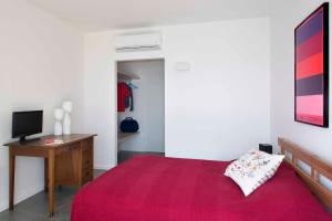 una camera con letto rosso, scrivania e TV di Le calandre a Ventimiglia