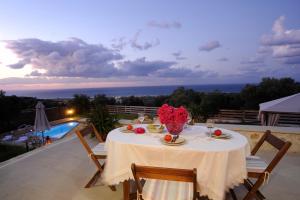 Kivotos Villa في Maroulás: طاولة مع الطعام والزهور فوق الفناء