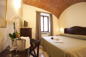a bedroom with a bed and a table with wine glasses at Albergo La Corte Albertina in Bra