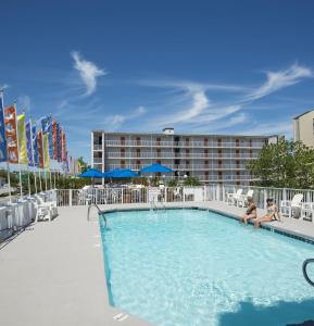 a swimming pool with chairs and umbrellas and a hotel at The Spinnaker in Ocean City