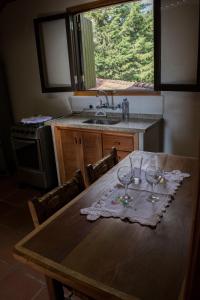 uma cozinha com uma mesa com duas taças de vinho sobre ela em Chalés entre Nuvens e Estrelas em Monte Verde