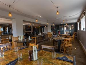 a restaurant with wooden tables and chairs and lights at The Sail Loft in Southwold