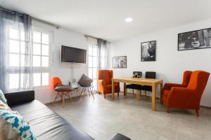 een woonkamer met oranje stoelen en een tafel bij PASACALLES Home by Cadiz4Rentals in Cádiz