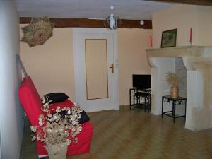 Una sala de estar con un sofá rojo y una chimenea. en Gite De La Tour De Rouilleres, en Ambierle
