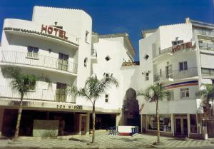 a large white building with palm trees in front of it at Kristal in Torremolinos