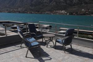 a group of chairs and tables on a balcony overlooking the water at Bjelica Apartments Kotor in Kotor