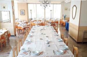 un lungo tavolo in un ristorante con tavoli e sedie bianchi di Hotel Moby Dick a Rimini