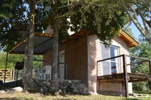 a small brick house with a porch and two trees at Cabañas Kumelkalechi in Los Reartes