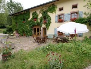 a building with a patio with tables and an umbrella at Auberge De La Charriole in Taintrux