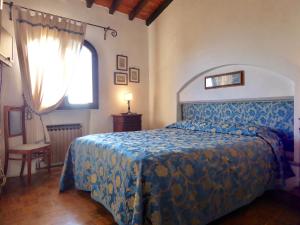 a bedroom with a bed with a blue comforter and a window at Bed Breakfast La Paggeria in Trespiano