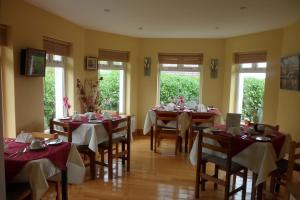 a dining room with tables with red and white tablecloths at Rockmount House B&B in Clifden